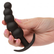 Hand holding a black silicone vibrating anal plug with a curved, beaded shaft and flared base.