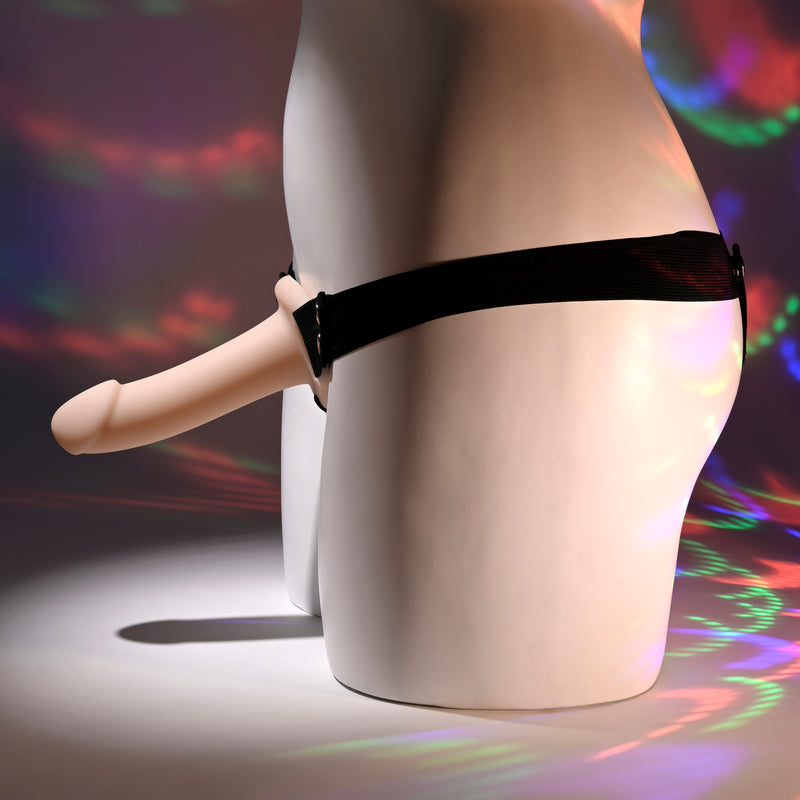 A white mannequin’s lower torso wears the Our First Hollow Strap-On Dildo + Harness Set - Vanilla. Colorful, circular light patterns shine on the mannequin and background. Great for beginners or those exploring strap-on play and ED solutions.