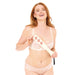 A smiling woman with long red hair wears light pink lingerie and holds the Peaches 'n Cream Impression Paddle with cut-out hearts against her chest, standing in front of a white background.