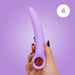 A hand with dark nail polish holds the Skins Care Curved Vaginal Dilators 3-Piece Set (Medium/Large), made of light purple medical-grade silicone with a circular handle, against a purple background. A white circle with the number 4 is in the upper right corner.