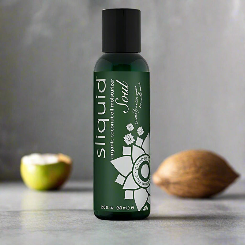 A 2-ounce (60 mL) bottle of Sliquid Soul Coconut Oil Moisturizer by Sliquid is displayed against a white background. The green bottle with a black cap features a silver floral design and text detailing the product's attributes, including apricot kernel oil for enhanced skin hydration.