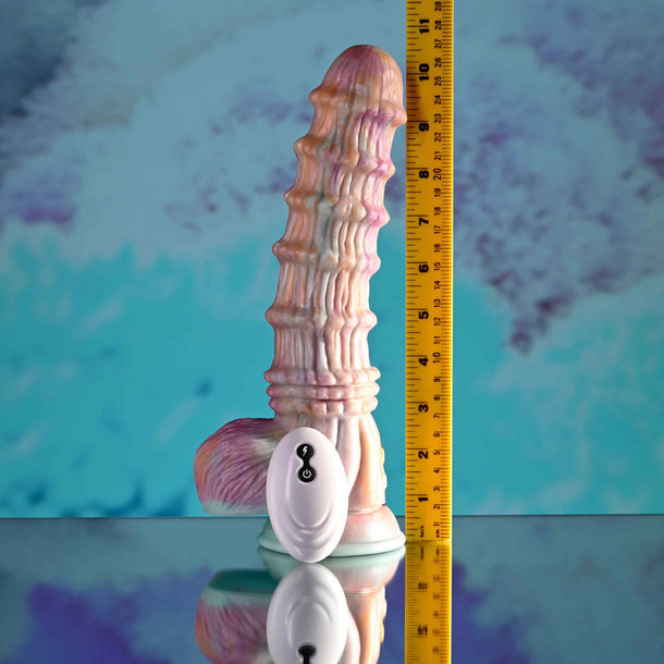The Fantasy Ultra Textured Vibrating Remote Control Creature Dildo, featuring a pale iridescent finish and textured silicone design, stands upright beside a yellow measuring tape and its white oval remote against a blue and purple backdrop.