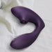 The Tracy's Dog OG Clitoral Sucking G-Spot Vibrator, in purple silicone with a curved design, rests on a white and gray striped fabric surface.