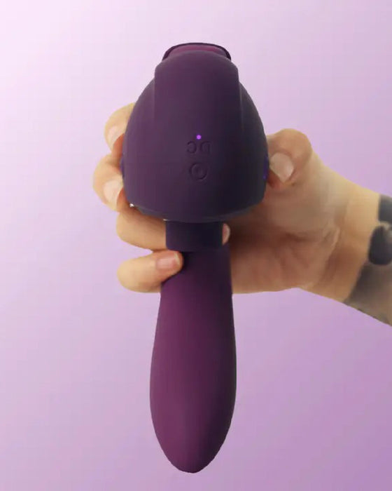 A hand holding Tracy's Dog OG 3 Clitoral Suction & G-Spot 2 in 1 Vibrator against a lilac background.