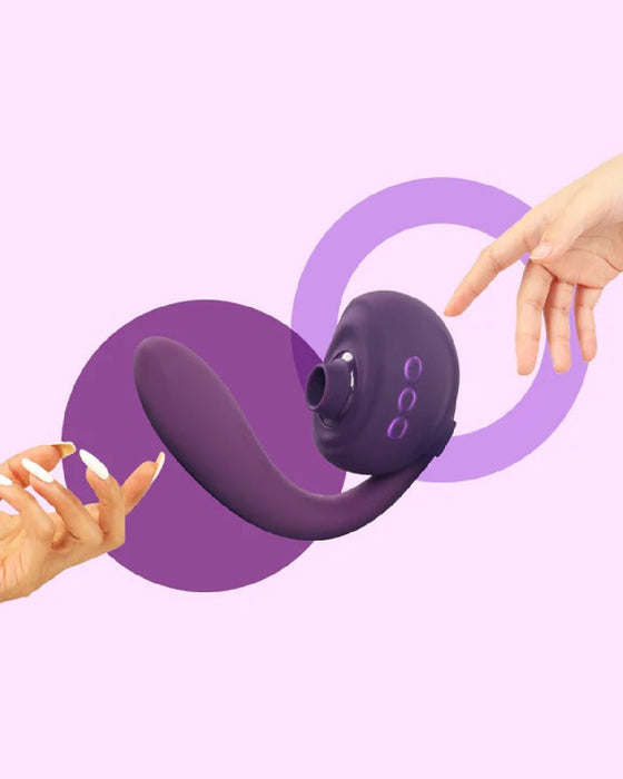 Two hands reaching towards a Tracy's Dog OG 3 Clitoral Suction & G-Spot 2 in 1 Vibrator on a pink and purple background.