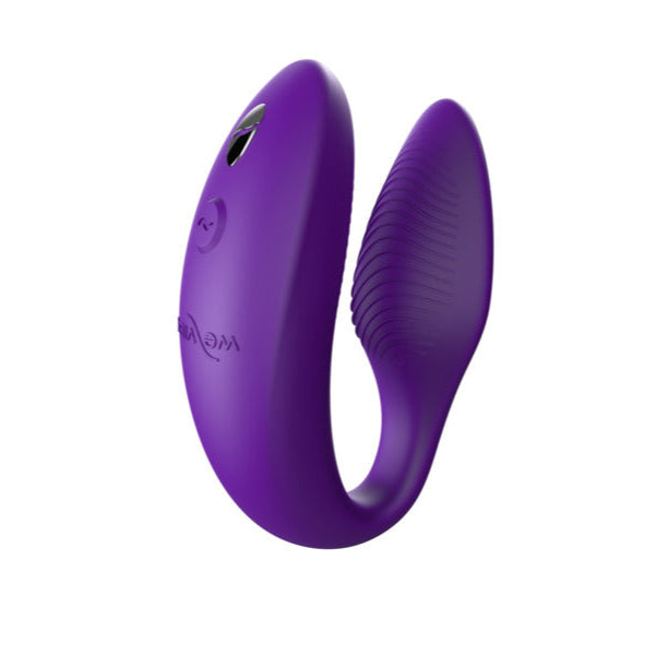 The We-Vibe Sync 2 is a purple, U-shaped wearable couples vibrator with ridged texture on one end and smooth control buttons outside, shown against a white background. Remote and app controlled.