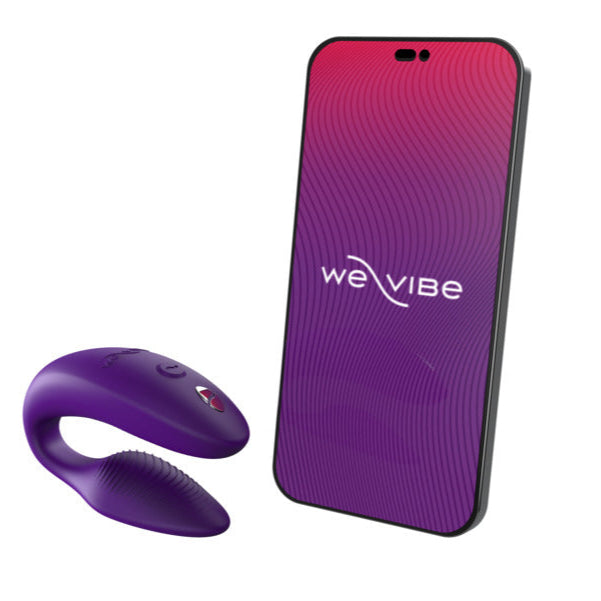 A We-Vibe Sync 2 Wearable Couples Vibrator in purple, with remote and app control, is shown next to a smartphone displaying the We-Vibe logo on a purple and pink gradient screen.