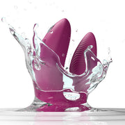 A dusty pink We-Vibe Sync 2 wearable couples vibrator, remote and app controlled, splashes into clear water, sending dynamic droplets and ripples across a white background.
