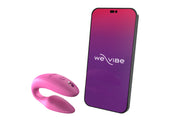 The We-Vibe Sync 2 Wearable Couples Vibrator in Dusty Pink is shown beside a smartphone with the We-Vibe logo on a purple and red gradient screen. This device offers remote and app control for couples.