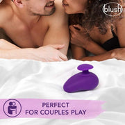 A couple lies in bed with a pink Wellness Palm Sense Rumbly External Vibrator with Finger Hold by Blush nearby. The image promotes intimacy with the text "blush" and "Perfect for Couples Play." Relaxed and smiling, the couple's focus is on each other while the toy is centrally placed on the white bedspread.