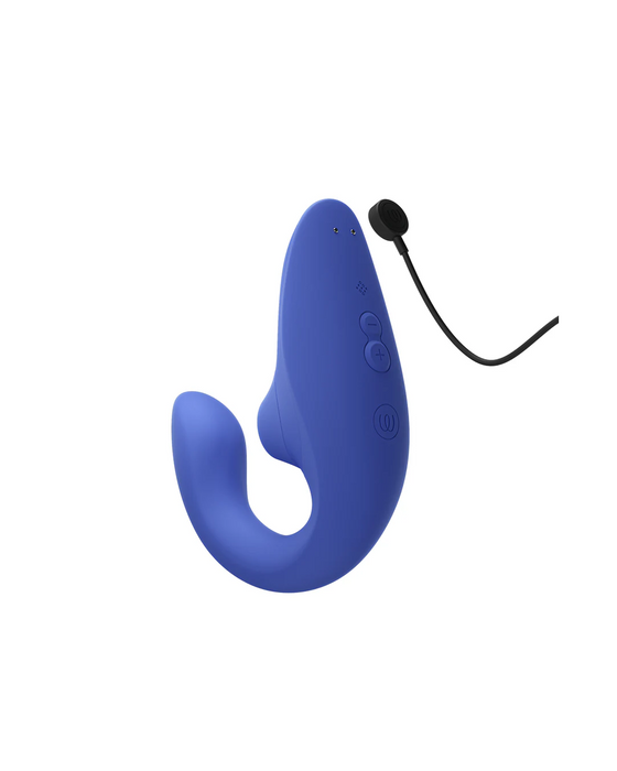 A blue, curved, ergonomic wearable device with control buttons and a magnetic charging cable attached. The gadget appears sleek and modern, with a smooth surface and minimalistic design, reminiscent of the chic elegance seen in Womanizer Pleasure Air Clitoral & G-Spot Rabbit - Blue products by Womanizer.