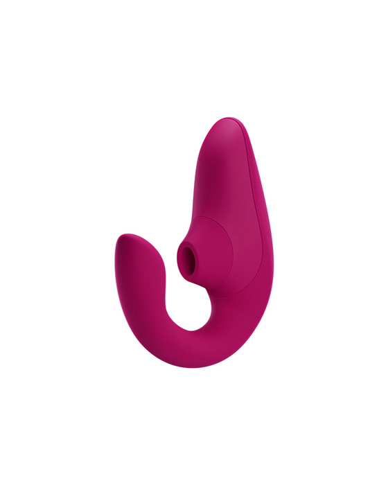 A pink, ergonomic adult toy with a curved design features a slender, rounded end on one side and a larger, contoured bulb with an opening on the other side for clitoral air pulsations. The Womanizer Blend Pleasure Air Clitoral & G-Spot Rabbit - Pink offers dual stimulation and has a smooth, seamless finish.