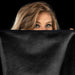 A person with long, light brown hair and bold eye makeup gazes over a luxurious Liberator Fascinator Throw Travel Sized Velvety Sex Blanket against a solid black background.