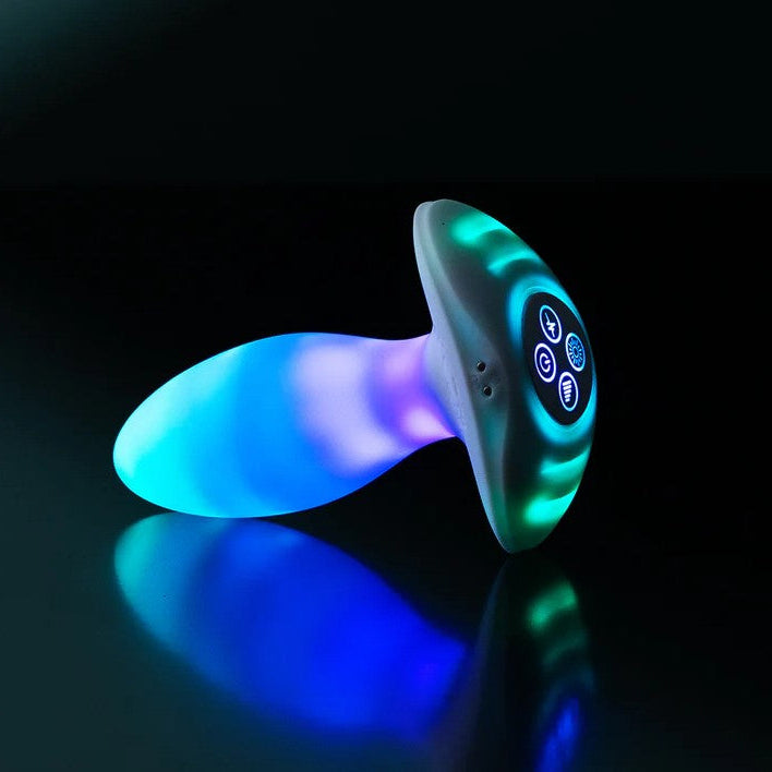 White silicone butt plug with a glowing blue and green LED light-up body and illuminated control panel.