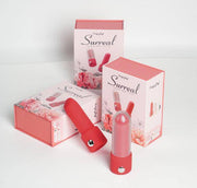 Red silicone lipstick vibrator with clear cap, next to two pink floral "Surreal" product boxes.