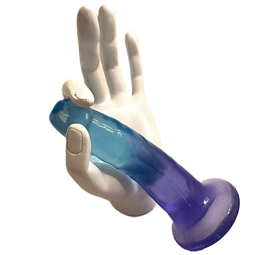 A white mannequin hand holds the Morning Dew Small 5 Inch Dildo with Suction Cup in blue, featuring a flared base and harness compatibility, isolated on a white background.