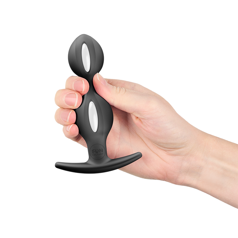 Hand holding a black silicone butt plug with white weighted inner balls and a flared base.