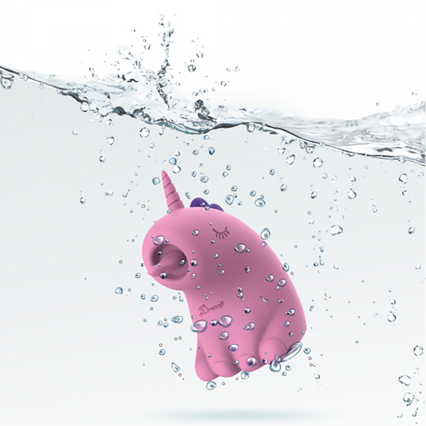 The Dreamy Licks – The Whimsical Unicorn Tongue Vibrator is a pink, cartoon-inspired unicorn made of body-safe silicone with a purple horn and closed eyes, pictured underwater with bubbles and splashes on a white background.