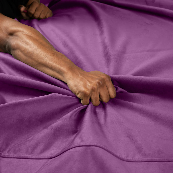 A close-up of a hand gripping the Liberator Fascinator Throw Velvety Waterproof Sex Blanket, creating folds and tension across its smooth, moisture-resistant surface.