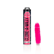 The Clone A Willy Vibrating Silicone Penis Casting Kit in Glow In the Dark Pink is shown with its packaging tube and realistic silicone mold on a white background.