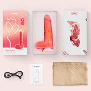 The Noctura Thrusting Silicone Dildo with App Control, in pink, is waterproof and features a suction base. It comes packaged with a USB charging cable, user manual, and beige storage pouch—all arranged on a light surface.