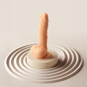 Realistic vanilla dildo with a lifelike glans and silky-smooth texture, standing on a circular pedestal.