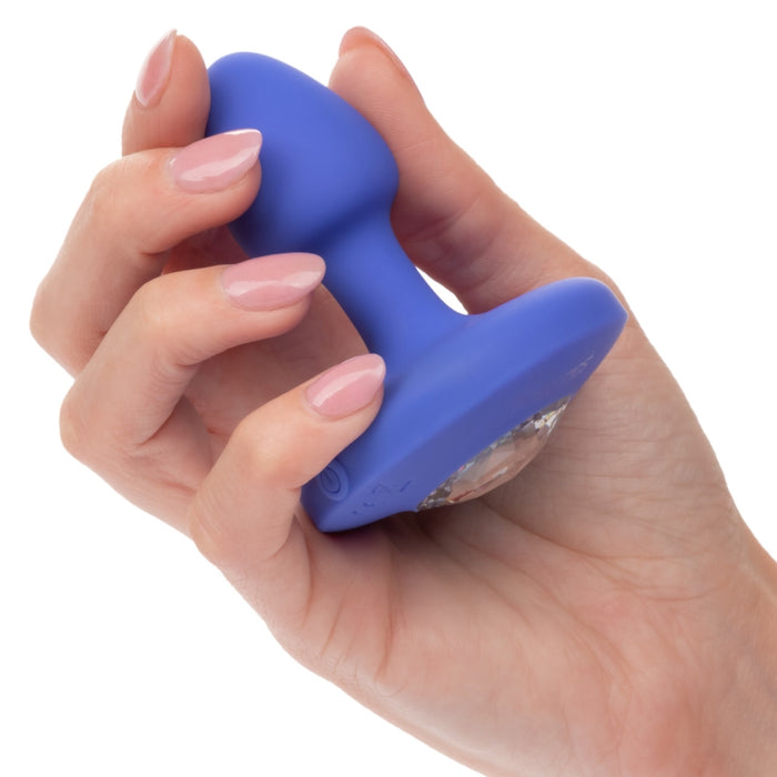 A manicured hand holds the Cheeky Gems Small Rechargeable Vibrating Butt Plug in blue, featuring a gem-like base—ideal for backdoor play—against a white background.