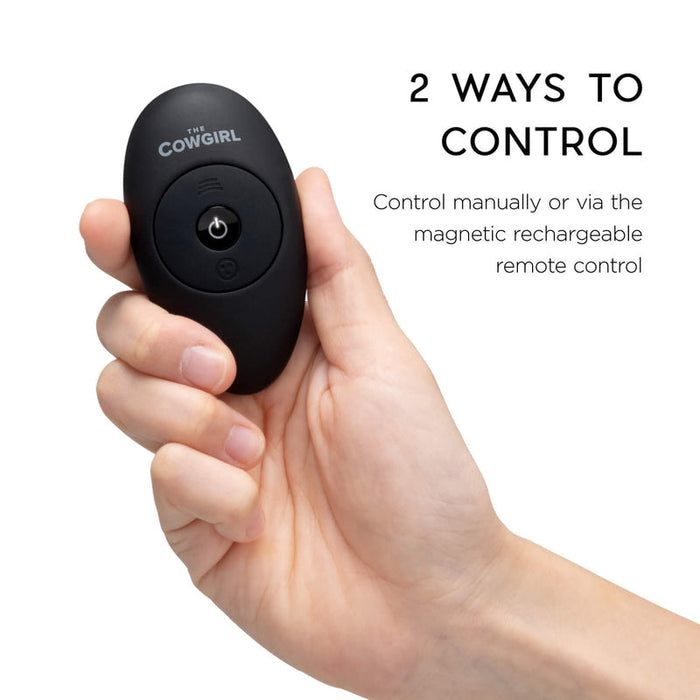 A hand holds a black oval remote labeled "The Cowgirl." Text reads: "Control The Cowgirl Saddle Sex Machine with Vibration, Thrusting & Rocking manually or via the magnetic rechargeable remote for seamless, hands-free pleasure.