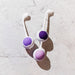 The Wellness Kegel Ball Training Kit for Pelvic Floor Health features two silicone Kegel balls with long handles in purple and pink, lying side by side on a light marble surface—ideal for effective pelvic floor strengthening.